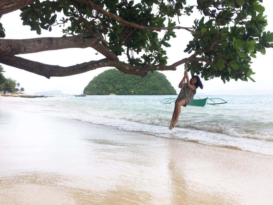 hanging from a tree above beach in el nido