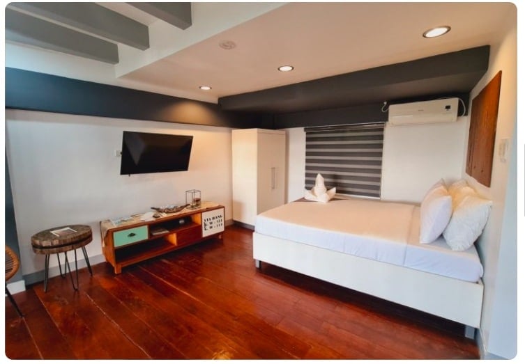 Moderna camera d'albergo a El Nido con letto grande, TV e pavimento in legno.