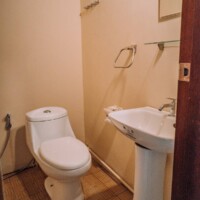 Toilet and sink in a cozy bathroom at Sand Island Main House, Philippines.