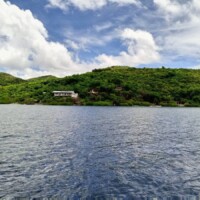 Main house on Sand Island with lush green hills in the background.