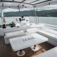 Yacht deck with seating area and table on a Leopard 58 catamaran, overlooking the sea and distant is.