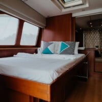 Luxurious Leopard 58 yacht bedroom featuring wooden furnishings and natural light from large windows.