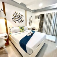 Modern hotel room at Princesa with white bedding, decorative wall art, and natural light.