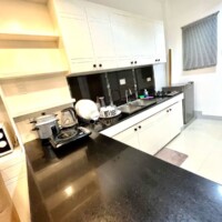 Kitchen with black countertops and white cabinets, equipped with appliances and utensils.