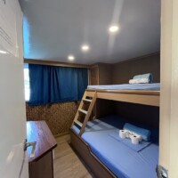Cozy bunk bed cabin on Dolphin Liveaboard with camera and linens.
