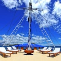 Siren Liveaboard deck featuring lounge chairs and a sailboat mast against a blue sky.