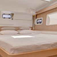 Yacht cabin with a large bed, windows, and cozy decor, perfect for relaxing during island hopping in.