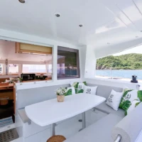 Yacht deck seating area with white cushions and island scenery in the background.