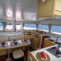Luxury yacht interior with dining area and kitchen, overlooking the sea.