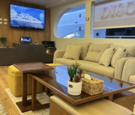 A cozy yacht lounge with sofa, coffee table, and tropical décor, offering a stylish and relaxing space for travelers exploring the Philippines. Elegant yacht lounge featuring comfortable seating, wooden accents, and ocean views—ideal for travel comfort in the Philippines.