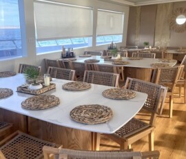 Elegant seaside restaurant with ocean views, wooden decor, and cozy table settings perfect for relaxing meals. Stylish ocean-view dining area in the Philippines with natural wood furniture and sea views.