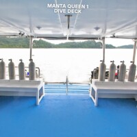 The Manta Queen 1 dive deck features oxygen tanks and space for divers, offering a safe and comfortable setup for exploring the Philippines' underwate. Dive deck with oxygen tanks on a boat in the Philippines.