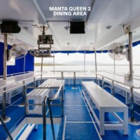 Relaxing dining space on the Manta Queen 2 cruise with scenic water views and comfortable seating. Manta Queen 2 dining area on a boat with seating and scenic water views.