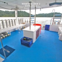 The dive deck of Manta Queen 2 features oxygen tanks, seating, and storage, offering a safe and organized space for divers exploring the Philippines. Dive deck with oxygen tanks and equipment on a boat in the Philippines.