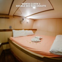 Cozy double bed room with pink bedding and decorative towel, perfect for a comfortable stay. Double Bed Non Ensuite Room at Manta Queen 2.