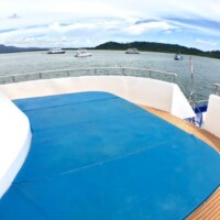 Scenic view from a boat deck showing calm waters, boats, and lush islands in the Philippines. View from a boat deck with boats and islands in the background.