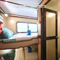 Interior of a cruise cabin featuring twin bunk beds with shared ensuite and a window view. Cozy twin bunk shared ensuite in a cruise cabin with window view.